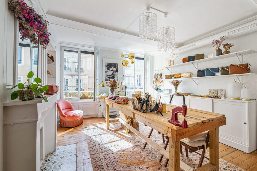 Photo présentant le showroom de Rosa Lopez avec une grande table en bois massif et des étagères présentant ses sacs en cuir